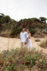 Side view of loving multiracial couple of newlyweds hugging while standing on sandy hill on wedding day — Stock Photo