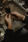 Manos de orfebre masculino anónimo usando herramienta manual para dar forma al anillo de metal en el taller - foto de stock