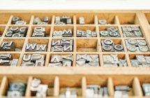 Ein Satz schäbiger Buchstaben aus Metall in Typografie in einer Holzkiste — Stockfoto