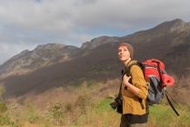 Seitenansicht einer nachdenklichen Reisenden mit Rucksack, die in den Bergen wandert und wegschaut — Stockfoto