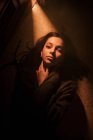 Von oben eine stumme junge Frau auf dem Boden liegend in einem dunklen Raum mit Licht, das durch die geöffnete Tür leuchtet und in die Kamera blickt — Stockfoto