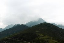 Gruesas nubes grises flotando en el cielo sobre verdes colinas en un día aburrido en el campo - foto de stock