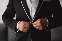 Cortar homem irreconhecível abotoando elegante casaco de noivo preto elegante enquanto se prepara para a cerimônia de casamento — Fotografia de Stock