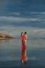Любящий мужчина обнимает женщину сзади, проводя вместе летний день на берегу моря — стоковое фото