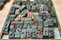 Набор металлических потрепанных букв и цифр в деревянном ящике в типографии — стоковое фото
