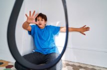 Helpless scared preteen boy sitting in corner while anonymous parent threatening with belt as domestic violence and child abuse concept — Stock Photo