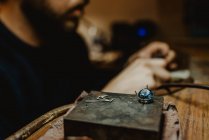 Gioielliere irriconoscibile che utilizza una lucidatrice professionale sul banco da lavoro mentre realizza un anello metallico in officina — Foto stock