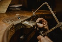 Анонимный ювелир резки металла с пилой во время изготовления украшений в мастерской — стоковое фото