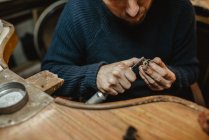 Gioielliere che utilizza la lucidatrice professionale sul banco da lavoro mentre fa anello metallico in officina — Foto stock