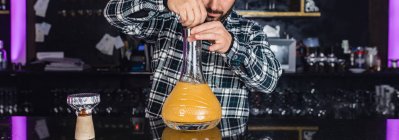 Обрізаний невпізнаваний чоловік готує великий скляний традиційний кальян у нічному клубі — стокове фото