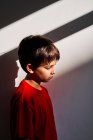 Visão lateral de triste indefeso menino pré-adolescente solitário com hematomas no rosto sofrendo de violência doméstica — Fotografia de Stock