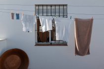 Laverie lavée suspendue sur corde à linge dans la cour de la maison de campagne avec murs blancs et fenêtre de grille — Photo de stock