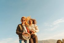 Angle bas des femmes riantes marchant ensemble sur la prairie verte dans la vallée de montagne au soleil — Photo de stock