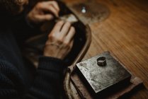 Мужчина ювелир с помощью ручного инструмента для формирования металлического кольца в мастерской — стоковое фото
