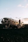 Young tourist standing on wrecked aircraft between deserted lands and blue sky — Stock Photo