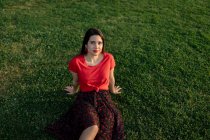 Tranquil female sitting on grass on meadow in park and enjoy sunset in summer — Stock Photo