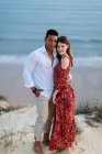 Loving multiracial couple in elegant clothes embracing on hill on background of evening in summer — Stock Photo