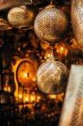 Lámparas ornamentales redondeadas de metal dorado con motivos en la tradicional tienda callejera de Marruecos - foto de stock