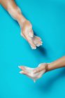 Ritaglia femmina anonima con unghie lunghe dimostrando mani con schiuma di sapone bianco su sfondo blu — Foto stock