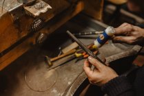 Anónimo orfebre martillando y expandiendo anillo en blanco en palo de metal mientras trabajaba en el taller - foto de stock
