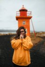 Счастливая женщина, стоящая возле оранжевого маяка у моря — стоковое фото