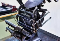 Máquina de tipografia retro shabby com detalhes metálicos colocados na bancada de madeira na tipografia — Fotografia de Stock