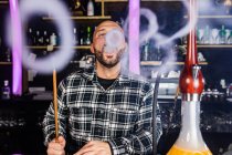 Мужчина курит традиционный кальян в ночном клубе — стоковое фото