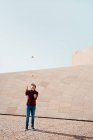 Повна довжина чоловіків, які виконують трюк з жонглювання клубами, стоячи проти сучасної кам'яної будівлі з незвичайною геометричною архітектурою — стокове фото