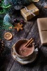 Зверху миска шоколаду з різдвяною прикрасою на дерев'яному столі поруч із загорнутими подарунками — стокове фото