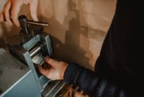 Orfebre irreconocible usando adorno de metal en la máquina mientras hace el anillo en el taller - foto de stock