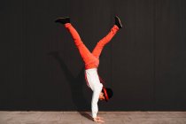 Seitenansicht eines unkenntlich agilen männlichen Zirkusartisten, der Handstand-Trick gegen schwarze Wand macht — Stockfoto