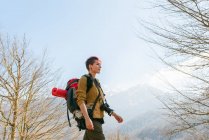 Vue latérale du voyageur féminin coûteux avec sac à dos marchant dans les montagnes regardant loin — Photo de stock