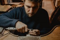 Manos de orfebre masculino usando herramienta manual para dar forma al anillo de metal en el taller - foto de stock