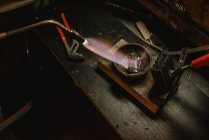 Oreficeria irriconoscibile metallo fuso per gioielli con fiamma ossidrica mentre in piedi vicino al banco da lavoro in officina — Foto stock
