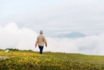 Rückansicht einer nicht wiedererkennbaren Seniorin, die morgens in hügeligem Gelände spazieren geht — Stockfoto