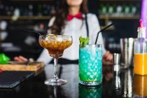 Blurred cropped unrecognizable female barkeeper in stylish outfit serving cocktail s with ice cubes while standing at counter in modern bar — Stock Photo