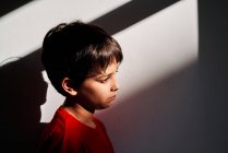 Vue latérale de triste garçon préadolescent solitaire sans défense avec des bleus sur le visage souffrant de violence familiale — Photo de stock