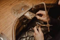 Orfèvre découpe le métal avec une scie lors de la fabrication de bijoux en atelier — Photo de stock