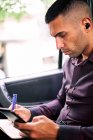 Konzentrierte hispanische männliche Unternehmer sitzt auf dem Beifahrersitz des Autos und schreibt in Planer während des Pendelns zur Arbeit — Stockfoto
