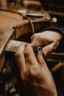 Manos de orfebre masculino anónimo usando herramienta manual para dar forma al anillo de metal en el taller - foto de stock