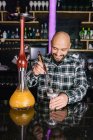 Glücklicher männlicher Barkeeper bereitet Schüssel mit Holzkohle für Wasserpfeife in einem Nachtclub vor — Stockfoto