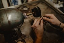 Руки анонімного чоловічого золотошукача з використанням ручного інструменту для формування металевого кільця в майстерні — стокове фото