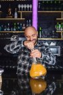 Feliz hombre preparando un gran vaso de narguile tradicional en un club nocturno - foto de stock