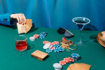 Corte fêmea irreconhecível com cartas e fichas jogando poker enquanto estiver sentado na mesa verde — Fotografia de Stock