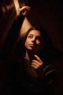 Dall'alto di silenziosa giovane femmina sdraiata sul pavimento nella stanza buia con la luce che brilla dalla porta aperta guardando altrove — Foto stock