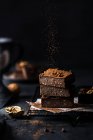 Composição de pequena pilha de saborosos cortes de brownie doce com pó no fundo preto — Fotografia de Stock