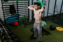 Strong male athlete exercising with heavy barbell disc during workout in gym — Stock Photo