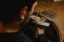 Goldschmied schneidet Metall mit Säge und fertigt Schmuck in Werkstatt — Stockfoto