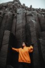 Молодой турист в очках позирует возле высокой черной каменной стены — стоковое фото