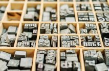 Набор металлических потрёпанных букв в деревянном ящике в типографии — стоковое фото